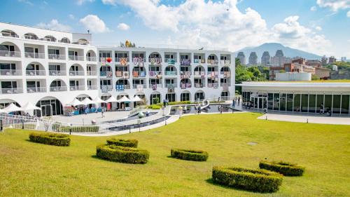 a large white building with a lawn in front of it at Golden Tulip FAB Hotel New Taipei in Tamsui