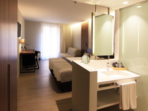 a hotel room with a bed and a sink and a mirror at Hotel Raval de la Mar in Vila-seca