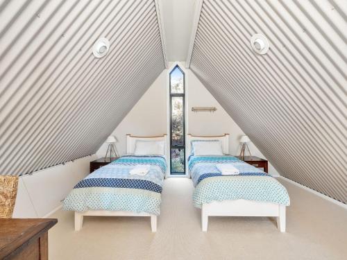 two beds in a attic room with a window at Sea Loft at Hyams Beach in Hyams Beach