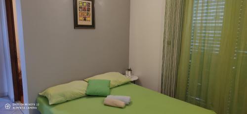 een slaapkamer met een groen bed met 2 kussens erop bij Apartments Marko in Drage