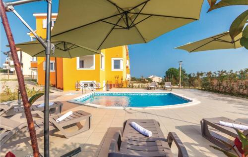 a pool with chairs and umbrellas next to a house at Amazing Apartment In Premantura With Wifi in Premantura