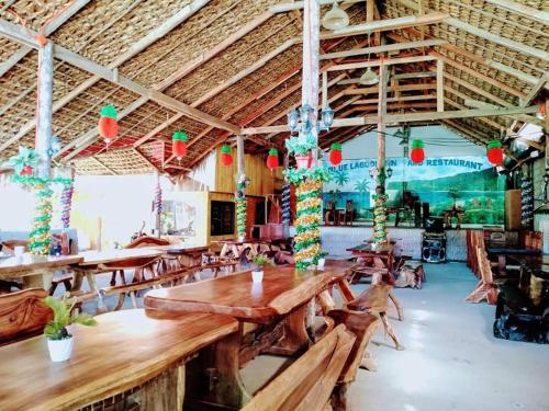 a restaurant with wooden tables and chairs and lights at Blue Lagoon Inn in Pagudpud