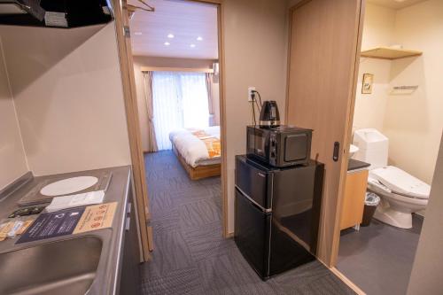 a small kitchen with a refrigerator and a bedroom at Stay SAKURA Kyoto Dragon in Kyoto
