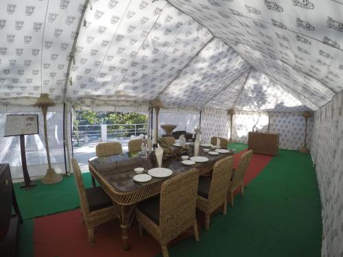 a large tent with a table and chairs in it at Samira's Birds & Butterflies Park-Spashram Ganga Beach Retreat in Rishīkesh