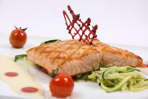 a piece of fish sitting on a plate with vegetables at Hotel zur Pfalz in Kandel