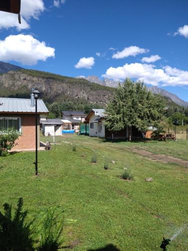 una casa en un campo con una montaña en el fondo en La posada de Icha en El Bolsón