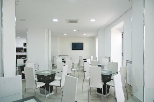 una sala da pranzo con sedie e tavoli bianchi e una TV di Hotel Regina a Caserta