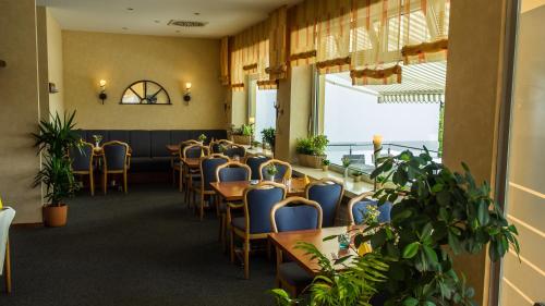 a dining room with tables and chairs and plants at Hotel Kieler Förde in Kiel