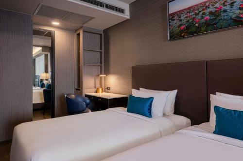 a hotel room with two beds with blue pillows at Wyndham Bangkok Queen Convention Centre in Bangkok