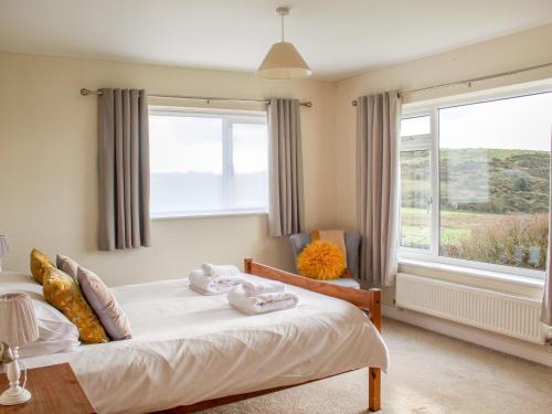 a bedroom with a bed and a large window at Rhos Helyg in Amlwch
