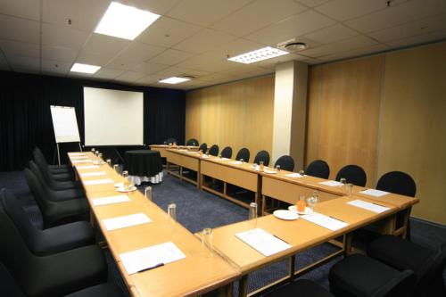 a conference room with long tables and chairs and a whiteboard at Coastlands Durban Self Catering Holiday Apartments in Durban