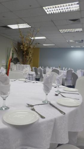 a room with white tables and chairs with plates and silverware at Coastlands Durban Self Catering Holiday Apartments in Durban
