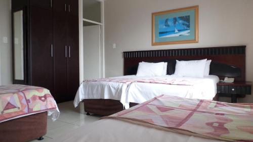 a bedroom with two beds and a dresser at Coastlands Durban Self Catering Holiday Apartments in Durban