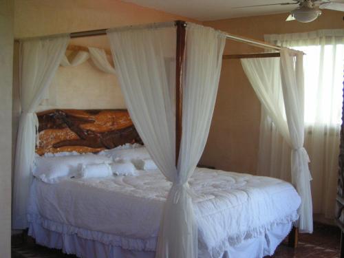 1 dormitorio con cama con dosel y cortinas blancas en Hotel Paradise Lagoon, en El Coacoyul