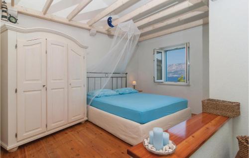 a bedroom with a bed with blue sheets and a window at Gorgeous Home In Postira With Kitchen in Postira