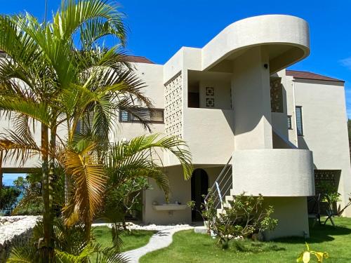 a building with a palm tree in front of it at Akabana Inn in Nakijin