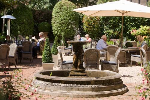 a fountain in a garden with people sitting at tables at Hotel du Vin Winchester in Winchester