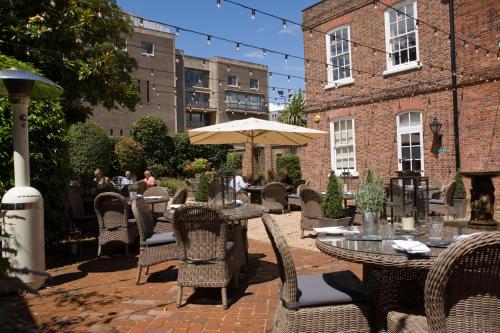 a patio with tables and chairs and an umbrella at Hotel du Vin Winchester in Winchester