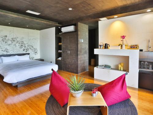a bedroom with a bed and a table with red pillows at 鸛巣（ムカカヴィラ コウノス) in Nakijin