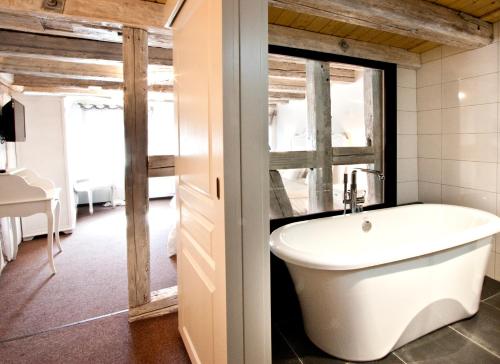 a bathroom with a bath tub and a sink at Chambre Le Hupsa Pfannala in Saint-Hippolyte