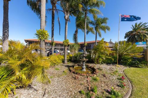un jardín frente a una casa con palmeras en Tuncurry Motor Lodge en Tuncurry