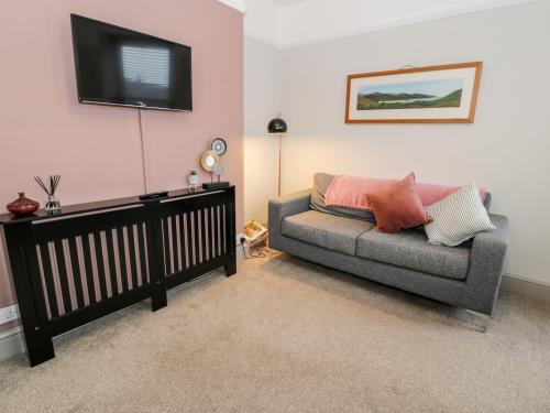 a living room with a couch and a flat screen tv at Rose Suite in Barmouth
