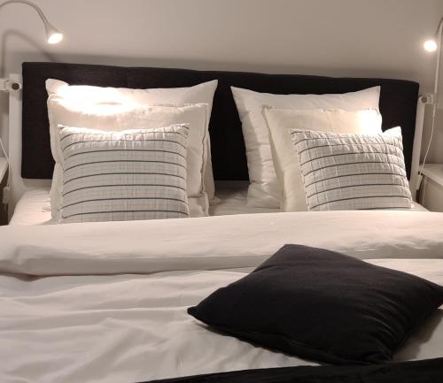 1 cama con almohadas blancas y almohada negra en URBAN APARTMENTS STUDIO No 3A Chorzów Katowice, FREE PRIVATE PARKING, en Chorzów