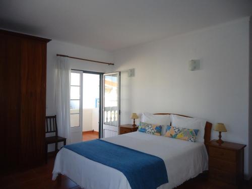 a bedroom with a bed with a blue blanket at Casa Mar Azul in Vila Nova de Milfontes