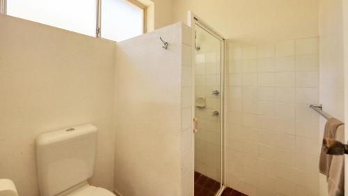 a white bathroom with a toilet and a shower at Bishops Lodge Narrandera in Narrandera