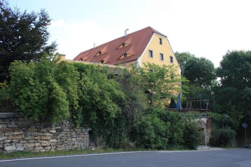 a yellow house with a red roof on a stone wall at Romantik Landhaus in Dresden