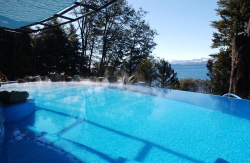 a large blue swimming pool with a view of the water at Design Suites Bariloche in San Carlos de Bariloche