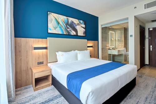 a bedroom with a large bed with a blue wall at Opero Hotel Southkey Johor Bahru in Johor Bahru