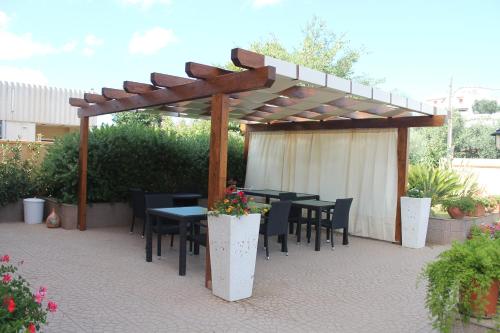 a patio with tables and chairs under a wooden pergola at B&B Zahir in Castro di Lecce