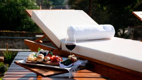 a plate of food and a glass of wine on a bed at Kkala Boutique Hotel in Salta