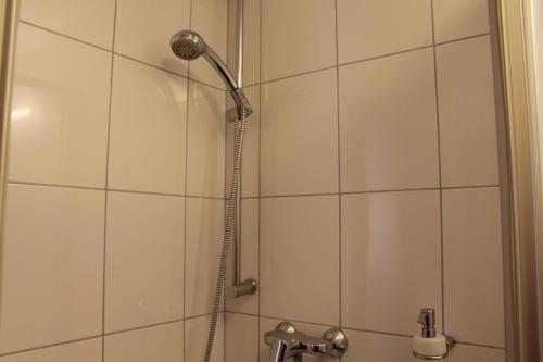 y baño con ducha con cabezal de ducha. en Hotel Andra München, en Múnich