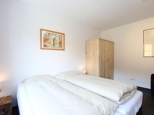 1 dormitorio con cama blanca y armario de madera en Apartment in Brixen im Thale near the ski area, en Feuring