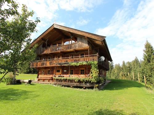 ein großes Holzhaus mit einem Hund davor in der Unterkunft Farmhouse in Hopfgarten in Brixental with garden in Hopfgarten im Brixental