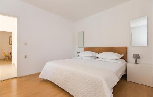 ein weißes Schlafzimmer mit einem Bett mit weißer Bettwäsche und Kissen in der Unterkunft Awesome Apartment In Makarska With Heated Swimming Pool in Makarska