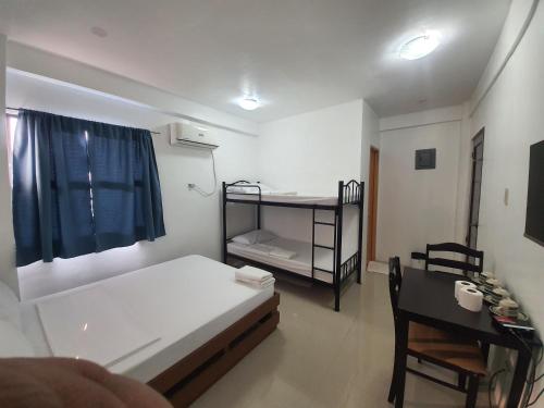 a small room with a bed and a desk and a bed and a table at Alicia Apartment in Manila