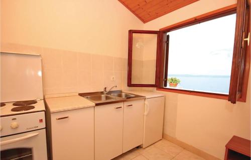 een keuken met een wastafel, een koelkast en een raam bij Lovely Apartment In Prigradica With Kitchen in Prigradica