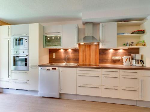 una cocina con armarios blancos y electrodomésticos blancos en Spacious Apartment in Tyrol with Mountain View, en Kappl