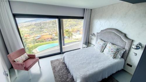 1 dormitorio con cama, silla y ventana grande en Villa Bonsai, en Arco da Calheta
