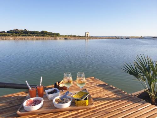 una mesa con dos copas de vino y comida en un lago en Peniche Alphonsia Maria, en Villeneuve-lès-Maguelonne