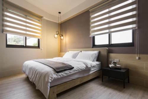 a bedroom with a bed with white pillows and windows at 風起文旅 The Wind Rises in Qishan
