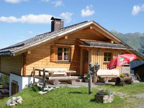 a log cabin with a picnic table and an umbrella at Apartment with balcony in Sankt Gallenkirch in Sankt Gallenkirch