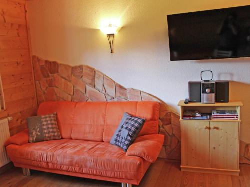 een oranje bank in een woonkamer met een tv bij Apartment with balcony in Sankt Gallenkirch in Sankt Gallenkirch