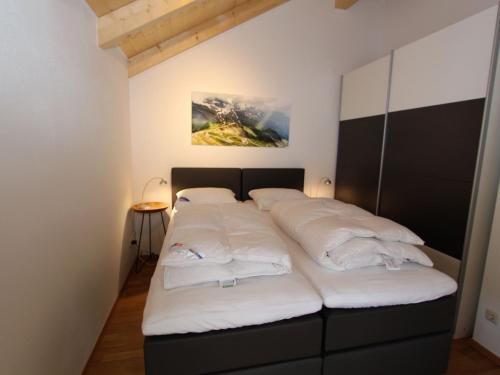Cama en habitación con almohadas blancas en Chalet in Kötschach near Family Ski Area, en Kötschach-Mauthen
