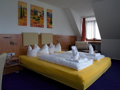Hotel Hembacher Hof في Rednitzhembach: غرفة فندق بسرير كبير ومخدات بيضاء