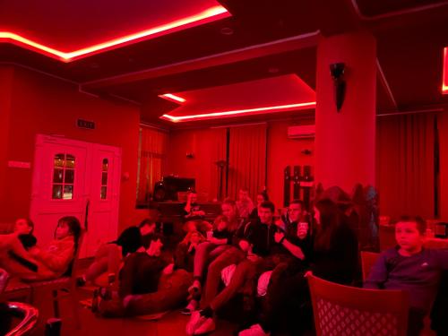 um grupo de pessoas sentadas numa sala com luzes vermelhas em Engi Panzió em Ocna de Sus