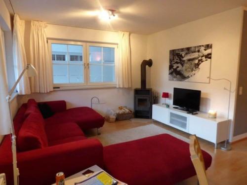 a living room with a red couch and a tv at Apartment in St Margarethen in the ski area in Sankt Margarethen im Lungau
